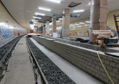 Baustelle der U-Bahn-Station Borsigwerke mit Gleisen, halbfertigem Bahnsteig aus Mauersteinen und Baugerüsten in einem unterirdischen Tunnel